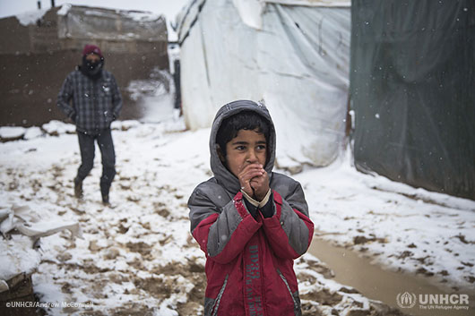 Mohammed, 10, tries to stay warm as snow falls in Faour tented settlement in the Bekaa Valley.