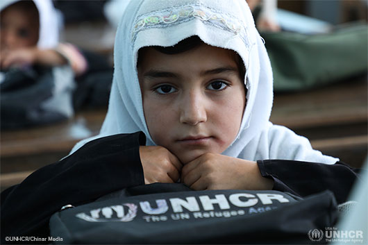 A Grade Three student sits hugs her UNHCR-distributed school bag at the Kahdistan Primary School.