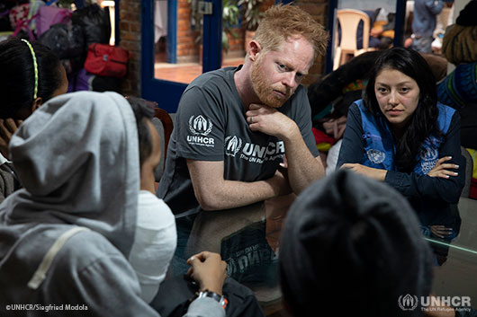 UNHCR supporter Jesse Tyler Ferguson listens to the stories of a family of Venezuelan refugees and migrants at a catholic shelter in Bogota.