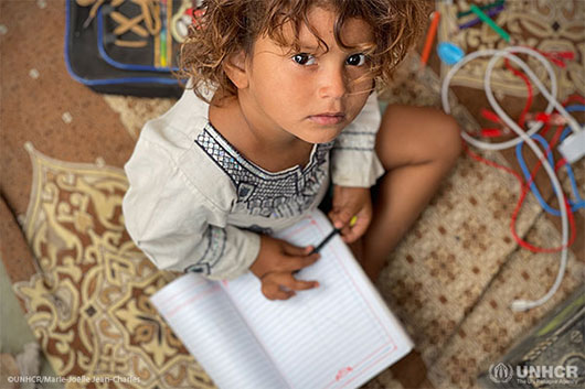 Four-year-old internally displaced Yemeni girl, Umaimah, practices writing in the makeshift shelter she shares with her parents and five siblings.