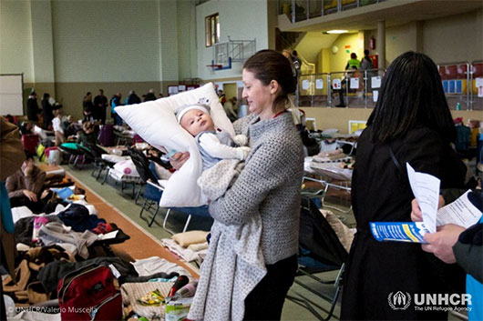Ukrainian refugee Valentina holds her 2-month-old nephew at a reception center in Poland.