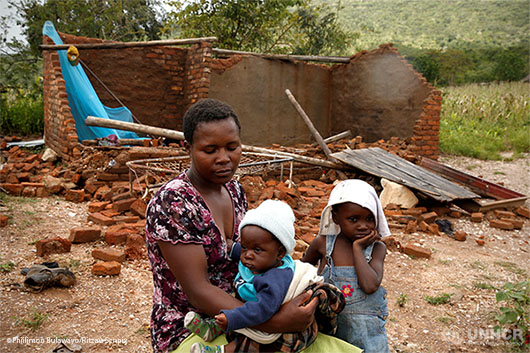 Nomatter Ncube and her kids sit beside their washed away family home in Zimbabwe following Cyclone Idai.