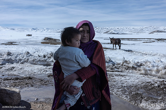 A refugee mother holding her small child in her arms