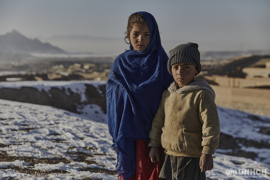 Two young refugee children standing in the winter cold.